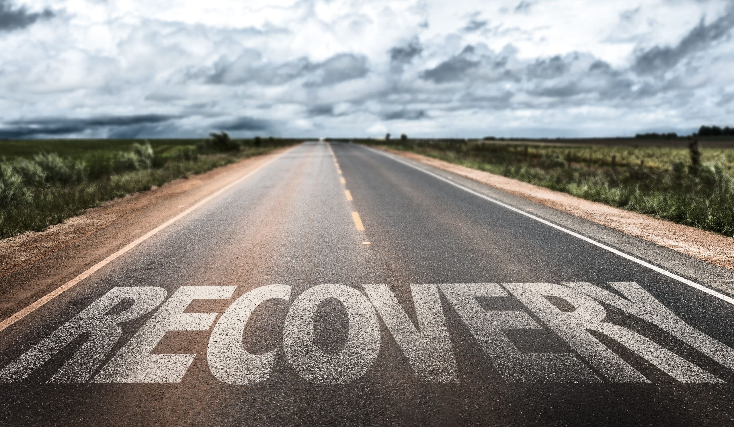 Exploring the Stages of Addiction Recovery Road extending into the distance, "recovery" imprinted on the asphalt